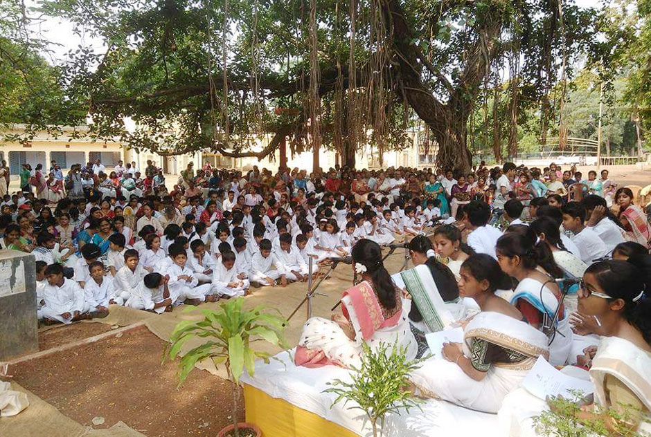 প্রতিবারই কবিগুরু রবীন্দ্রনাথ ঠাকুরের জন্মদিনকে ঘিরে মুখরিত হয়ে উঠে বাঙালির চারপাশ। অবাধ আনন্দ ছড়িয়ে পড়ে গোটা পশ্চিমবঙ্গে। শুক্রবার (২৫ বৈশাখ/৮ মে) কবিগুরুর ১৫৯তম জন্মবার্ষিকী। কিন্তু করোনা আতঙ্ক থমকে দিলো এবারের রবীন্দ্রজয়ন্তী উৎসব। অন্যান্যবার রবীন্দ্রজয়ন্তীতে গোটা পশ্চিমবঙ্গ ধ্বনিত হতো রবীন্দ্রসংগীতে। কিন্ত এবারের চিত্রটা একেবারেই ভিন্ন। করোনার জেরে বিশ্বভারতীতে বন্ধ রবীন্দ্রজয়ন্তী উৎসব! যদিও এই ব্যাপারে আনুষ্ঠানিকভাবে কোনো মন্তব্য করেনি বিশ্বভারতী কর্তৃপক্ষ। এদিন সকাল থেকেই উপাসনা মন্দিরের সামনের রাস্তায় অধিক সংখ্যক নিরাপত্তারক্ষী মোতায়েন করা হয়েছে। যাতায়াতের ওপর বেশ কিছু বিধিনিষেধ আরোপ করা হচ্ছে। জানা গেছে, কোনো সাংস্কৃতিক আনুষ্ঠান না হলেও উপাচার্যসহ বেশ কয়েকজন কর্মকর্তা ক্যাম্পাসে গিয়ে রবীন্দ্রনাথের চেয়ারে মাল্যদান করবেন। নমঃ নমঃ করেই এবার কবি-প্রণাম সারবে বিশ্বভারতী। স্বাভাবিকভাবেই মন খারাপ পড়ুয়াদের। গোটা বছর ধরে এই দিনটার প্রতীক্ষায় থাকে তারা। কত চর্চা, কত আয়োজন-করোনার জেরে সবই বিফলে। তাই মন ভারাক্রান্ত। ১৯১০ সালে রবীন্দ্রনাথের জীবদ্দশায় বিশ্বভারতীতে রবীন্দ্রজয়ন্তী পালন করা শুরু হয়েছিল। পরের বছর বিশ্বকবির পঞ্চশতম জন্মবর্ষ ঘটা করে পালিত হয়েছিল বিশ্ববিদ্যালয় প্রাঙ্গণে। সেসময় শান্তিনিকেতনে গ্রীষ্মের প্রচুর দাবদাহ থাকায়, রবীন্দ্রনাথ ঠিক করেছিলেন ২৫ বৈশাখের পরিবর্তনে ১লা বৈশাখ রবীন্দ্রজয়ন্তী পালন করা হবে। তারপর থেকে তেমনই রীতি ছিল সেখানে। যদিও সুজিত বসু উপাচার্য থাকাকালীন নিয়ম বদলায়। ১লা বৈশাখও অনুষ্ঠান হয় ঠিকই, কিন্তু ২৫ বৈশাখই ঘটা করে রবীন্দ্রজয়ন্তী পালন করা শুরু হয়। এ বছর যেন এক অন্য ২৫ বৈশাখ। শান্তিনিকেতনে আনাচে-কানাচে আজ ধ্বনিত হচ্ছে না কবিগুরুর গান। চতুর্দিক খাঁ-খাঁ করেছে। করোনা ঘিরে সর্বত্রই সতর্কতা। তবে আগামি বছর চিত্রটা পাল্টাবে- এই প্রত্যাশাই রবীন্দ্র